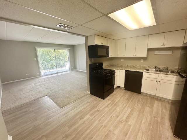 kitchen featuring black appliances, a drop ceiling, white cabinetry, and sink