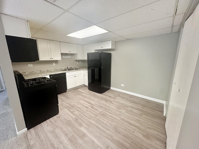 kitchen with a paneled ceiling, white cabinetry, sink, and black appliances