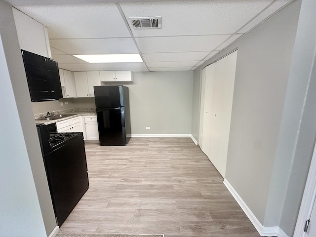 kitchen featuring white cabinetry, sink, light hardwood / wood-style flooring, a paneled ceiling, and black appliances