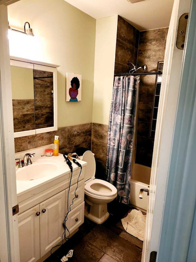 full bathroom with vanity, toilet, shower / bath combo with shower curtain, and tile walls