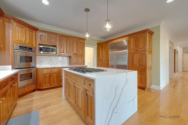 kitchen featuring tasteful backsplash, built in appliances, pendant lighting, a kitchen island, and ornamental molding