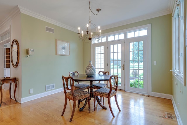 dining room featuring crown molding, french doors, light hardwood / wood-style floors, and a notable chandelier