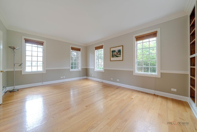 empty room with plenty of natural light, light hardwood / wood-style floors, and ornamental molding