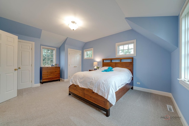 bedroom featuring light carpet, vaulted ceiling, and a closet