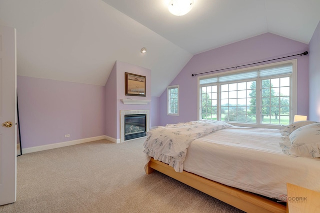 carpeted bedroom featuring a tiled fireplace and vaulted ceiling