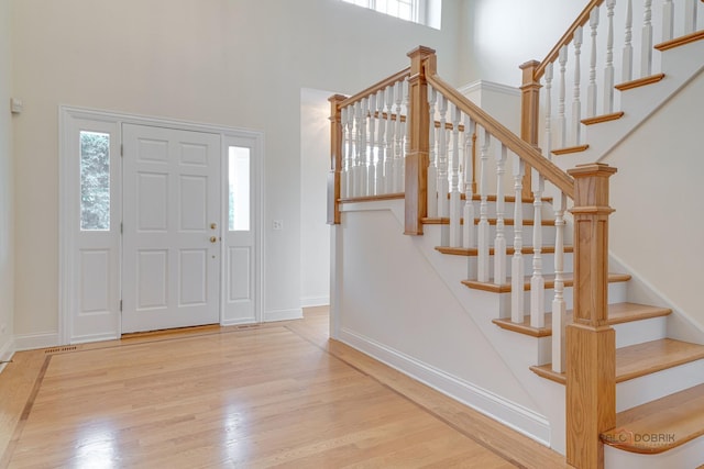 foyer entrance featuring wood-type flooring and a high ceiling