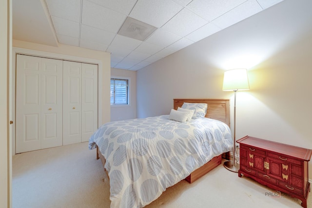 bedroom with carpet flooring, a drop ceiling, and a closet