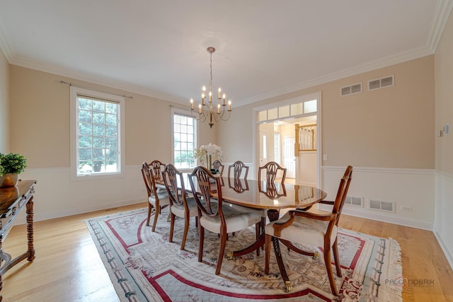 dining room with light hardwood / wood-style flooring, an inviting chandelier, and ornamental molding