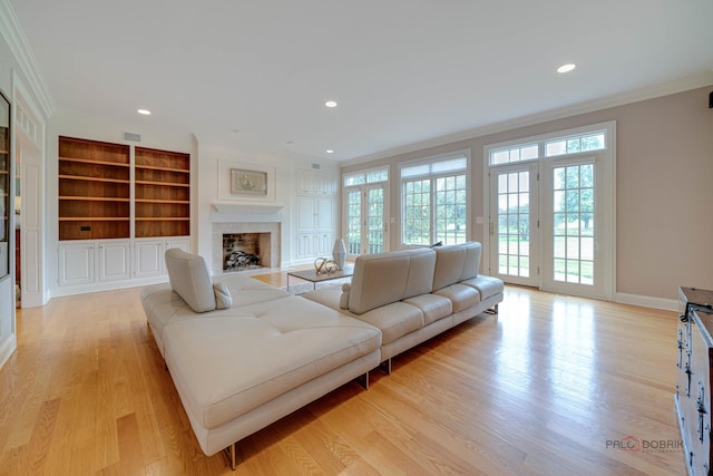 living room with built in shelves, light hardwood / wood-style floors, french doors, and crown molding