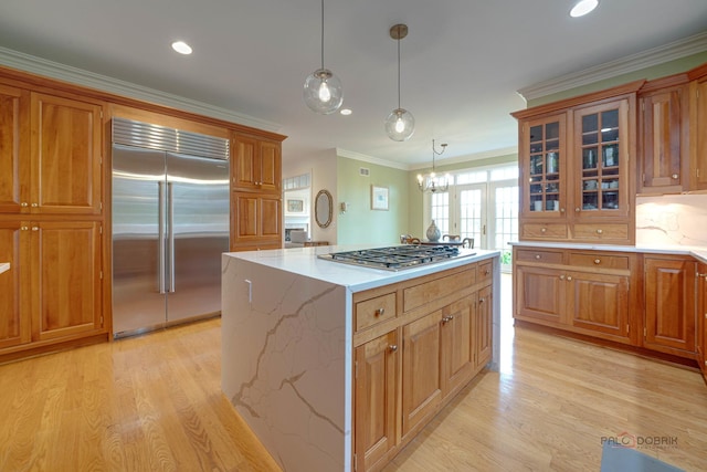 kitchen with a center island, crown molding, appliances with stainless steel finishes, decorative light fixtures, and light hardwood / wood-style floors