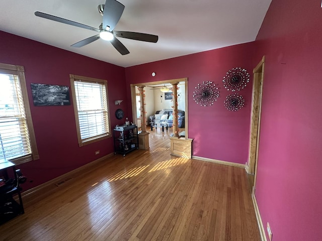 interior space with hardwood / wood-style flooring, ceiling fan, and decorative columns