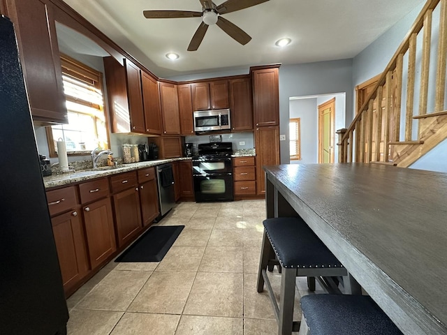 kitchen featuring black appliances, sink, ceiling fan, light stone countertops, and light tile patterned floors