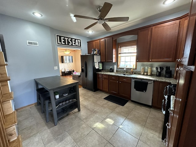 kitchen with black appliances, ceiling fan, light stone counters, and sink