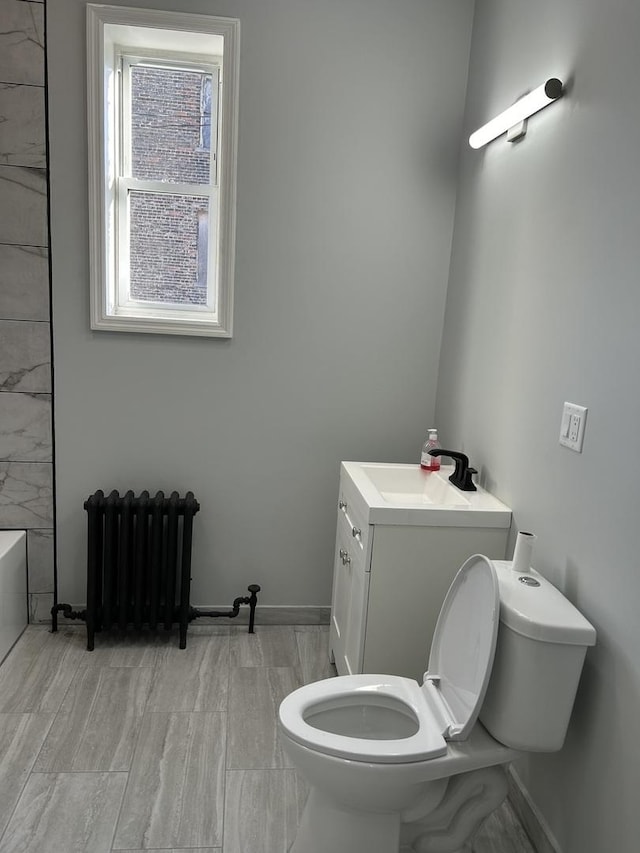 bathroom with vanity, toilet, radiator, and a tub