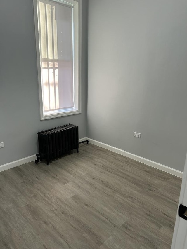 unfurnished room featuring hardwood / wood-style flooring and radiator