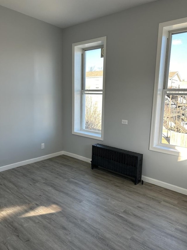 empty room with wood-type flooring and radiator heating unit