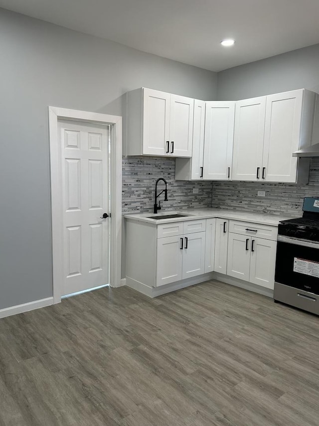 kitchen with white cabinets, light wood-type flooring, and stainless steel range oven