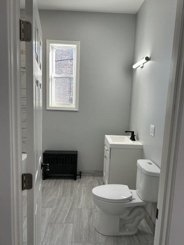 bathroom featuring radiator heating unit, vanity, and toilet