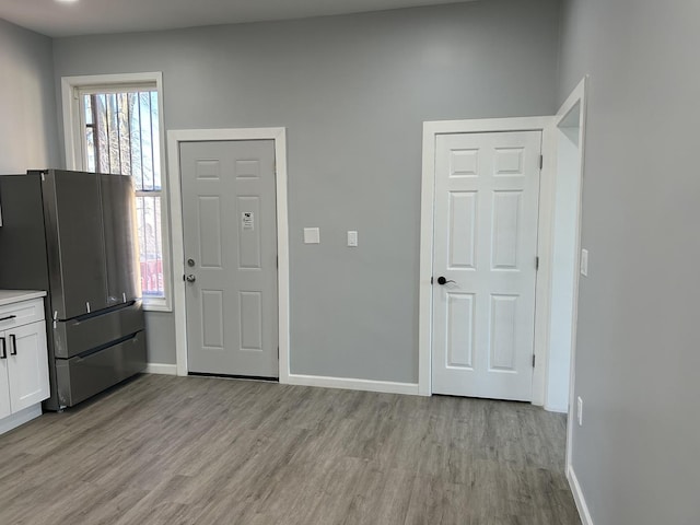 interior space featuring white cabinets, stainless steel fridge, and light hardwood / wood-style flooring