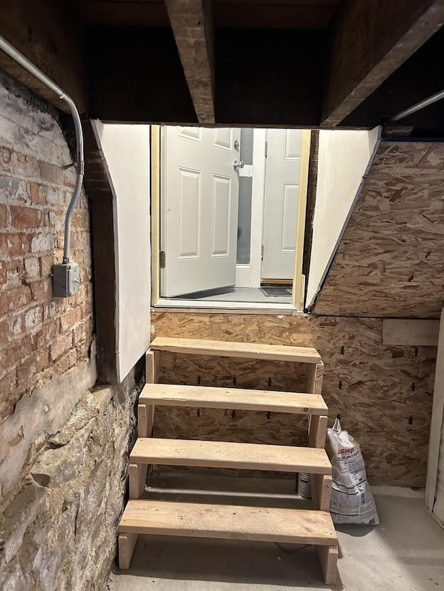 staircase with concrete flooring and brick wall