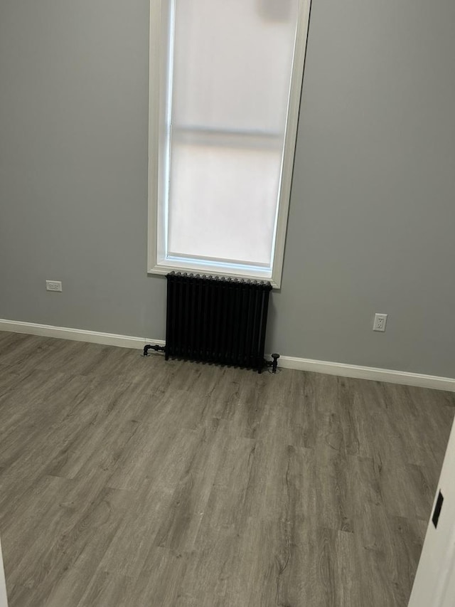 empty room featuring radiator heating unit and wood-type flooring