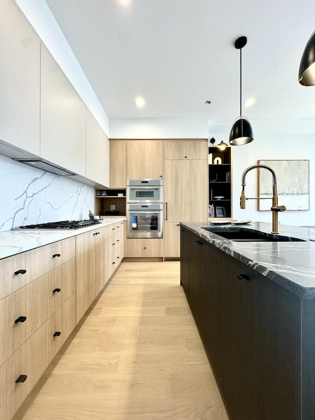 kitchen with pendant lighting, appliances with stainless steel finishes, dark stone countertops, sink, and backsplash