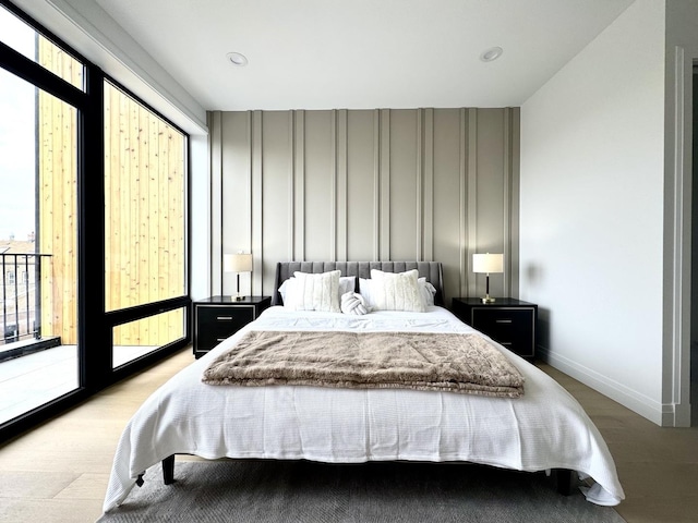 bedroom with access to exterior, multiple windows, and light hardwood / wood-style floors