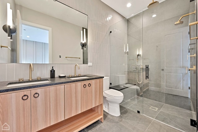 bathroom with an enclosed shower, vanity, decorative backsplash, tile walls, and toilet