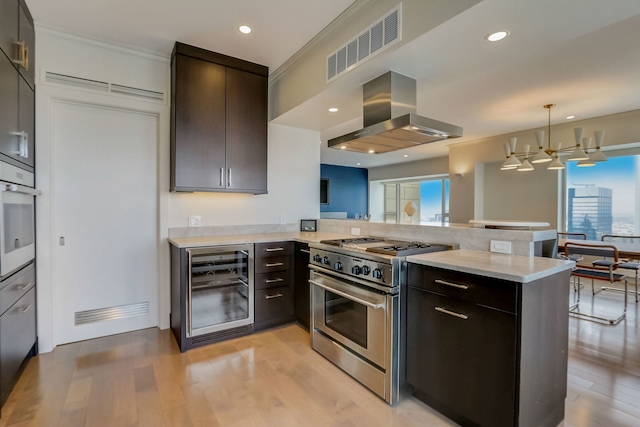 kitchen with exhaust hood, white oven, stainless steel stove, kitchen peninsula, and beverage cooler