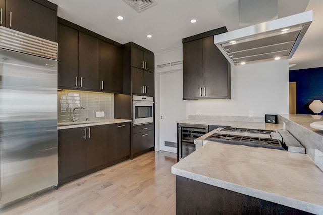 kitchen featuring sink, light wood-type flooring, range hood, stainless steel appliances, and beverage cooler