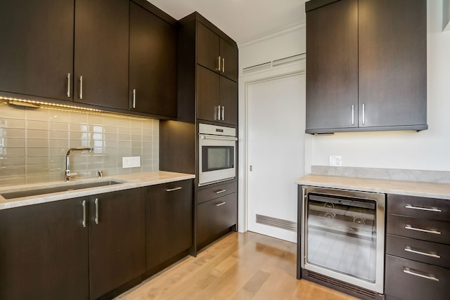 kitchen featuring dark brown cabinets, wall oven, wine cooler, and sink