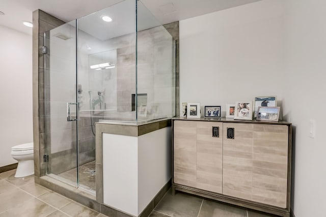 bathroom with tile patterned flooring, toilet, and an enclosed shower