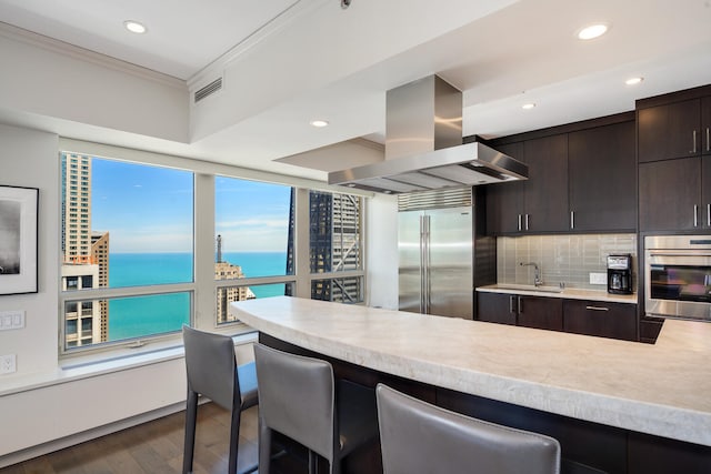 kitchen with a breakfast bar area, island range hood, stainless steel built in fridge, and a water view