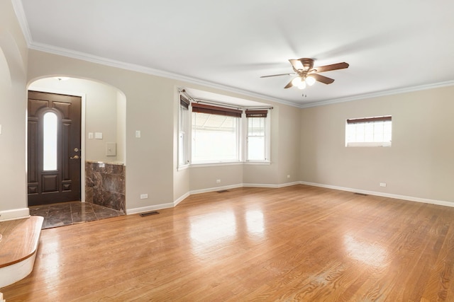 foyer entrance featuring a healthy amount of sunlight, light wood-type flooring, ceiling fan, and crown molding