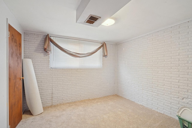 carpeted spare room with brick wall