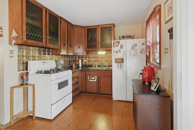 kitchen featuring decorative backsplash, sink, white appliances, and light hardwood / wood-style flooring