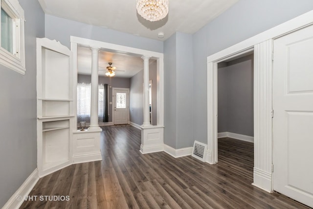 foyer with ceiling fan with notable chandelier, dark wood-type flooring, and ornate columns