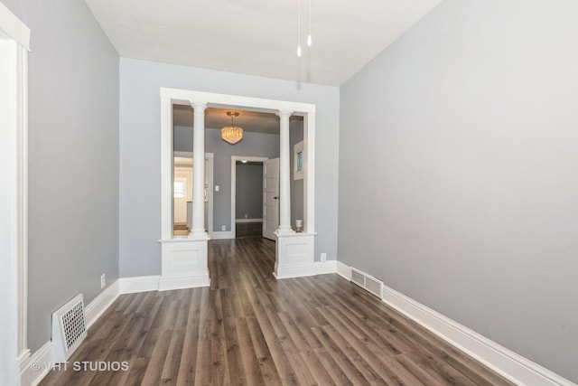 empty room featuring decorative columns and dark hardwood / wood-style flooring