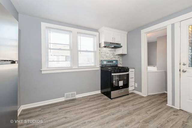 kitchen with tasteful backsplash, stainless steel gas range, white cabinetry, and light hardwood / wood-style flooring