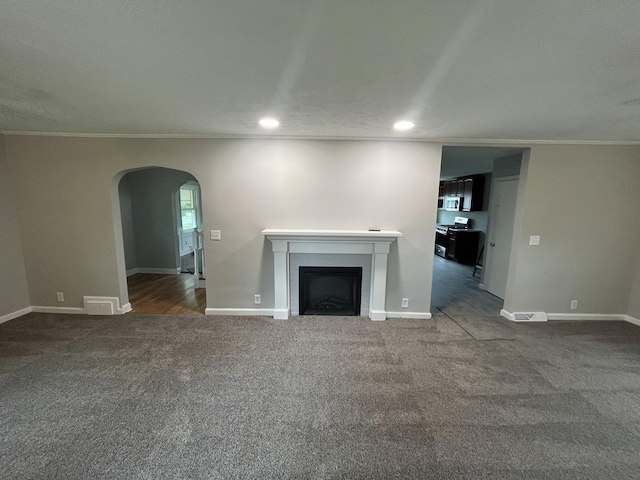 unfurnished living room featuring ornamental molding and dark colored carpet