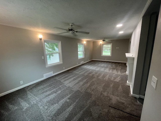 unfurnished living room featuring ceiling fan, dark carpet, a textured ceiling, and a wealth of natural light