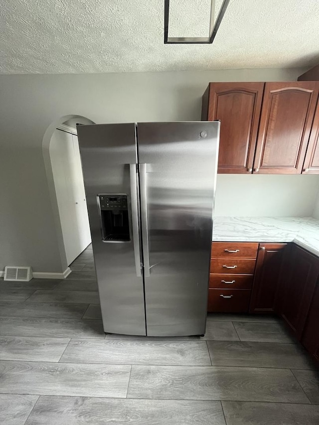 kitchen featuring a textured ceiling and stainless steel refrigerator with ice dispenser