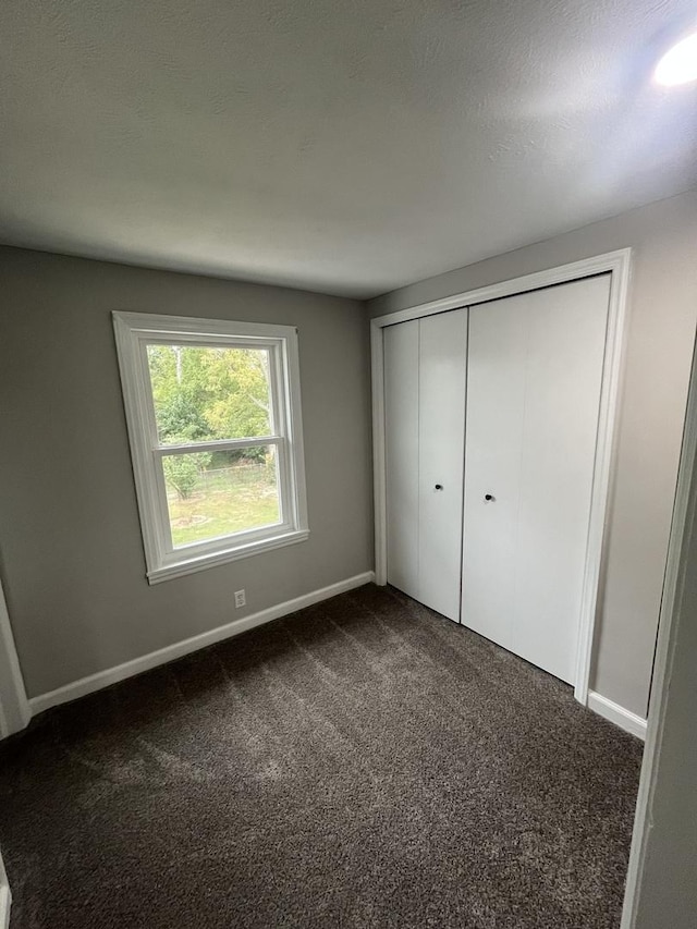 unfurnished bedroom featuring a closet and dark colored carpet