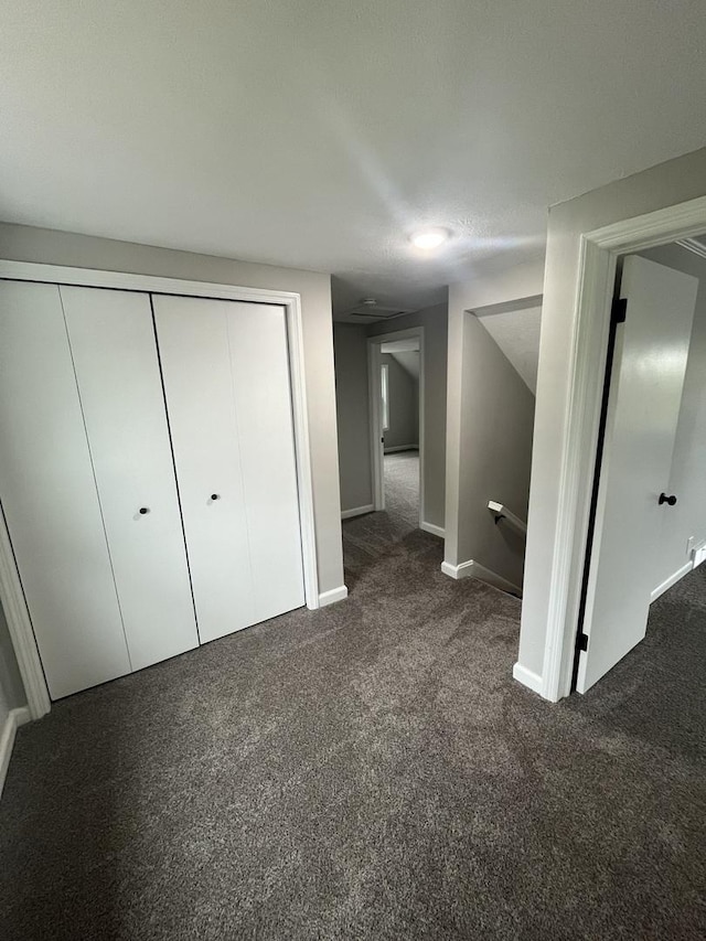 unfurnished bedroom featuring dark carpet and a closet