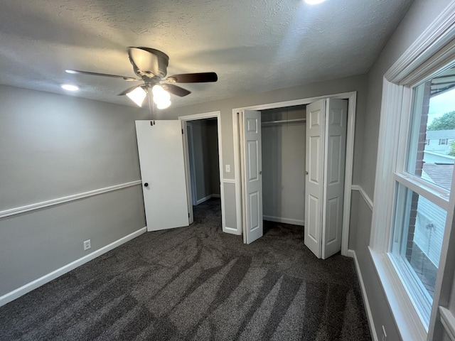 unfurnished bedroom featuring dark colored carpet, a textured ceiling, ceiling fan, and a closet