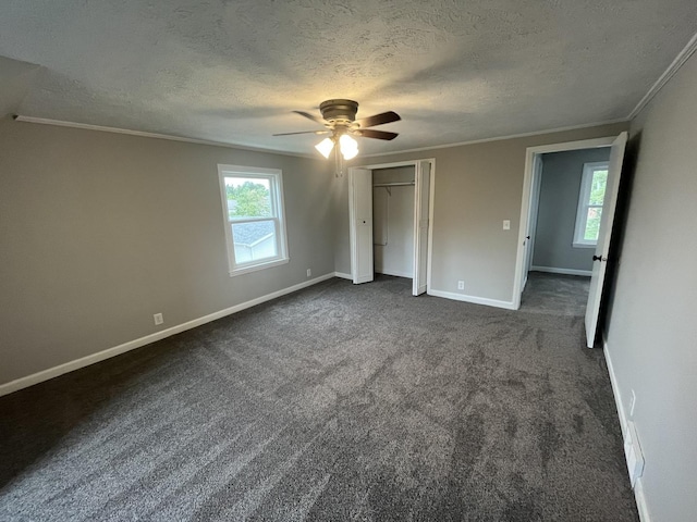 unfurnished bedroom with crown molding, ceiling fan, multiple windows, and dark colored carpet