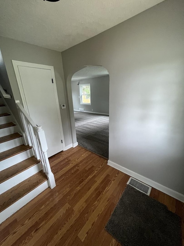 staircase with hardwood / wood-style flooring and a textured ceiling