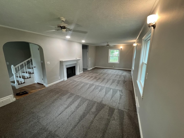 unfurnished living room with ceiling fan, crown molding, carpet floors, and a textured ceiling