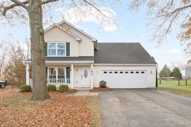 traditional-style home with a porch, roof with shingles, an attached garage, and aphalt driveway