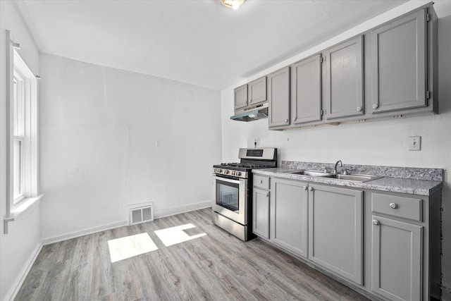 kitchen featuring gray cabinetry, sink, light wood-type flooring, and stainless steel gas range